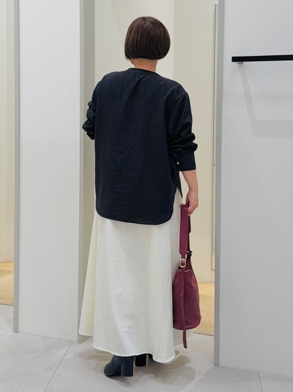 ブラック系のシャツ/ブラウス、ホワイト系のスカート、レッド系のショルダーバッグを着用したレディースの秋コーディネートの4枚目の写真