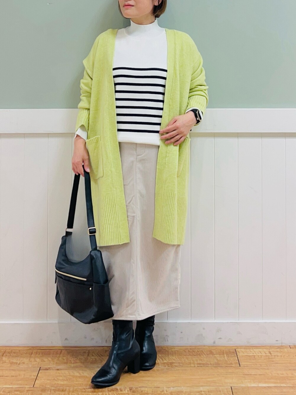 ブラック系のニット/セーター、イエロー系のカーディガン/ボレロ、ベージュ系のスカートを着用したレディースの秋コーディネートの5枚目の写真