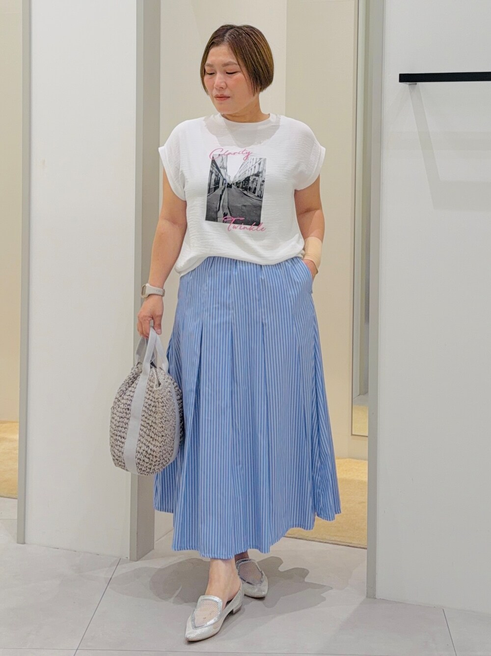 ホワイト系のTシャツ/カットソー、ブルー系のスカート、グレー系のトートバッグを着用したレディースの夏コーディネートの2枚目の写真