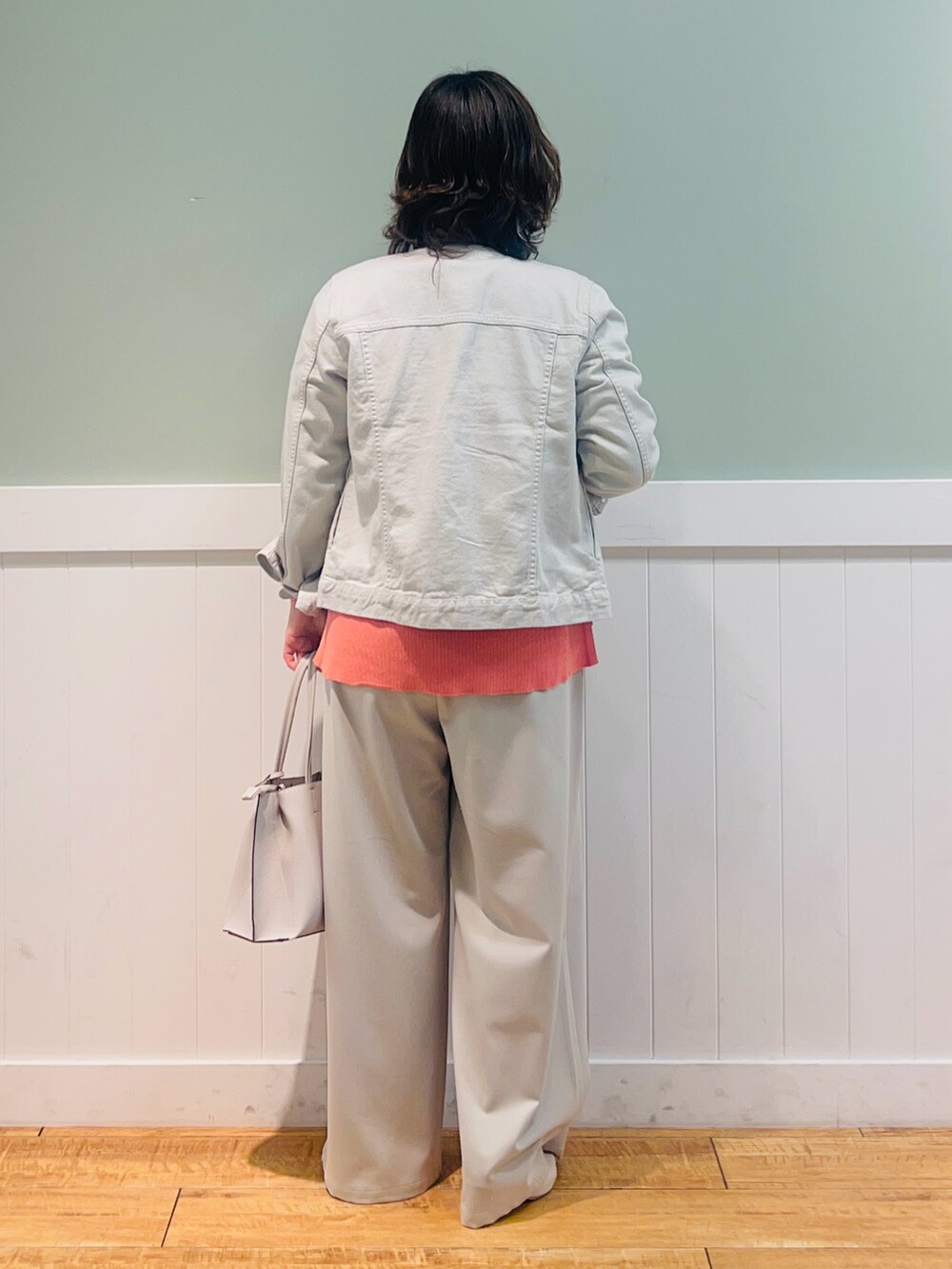 グレー系のデニムジャケット、ピンク系のニット/セーター、グレー系のトートバッグを着用したレディースの春コーディネートの3枚目の写真