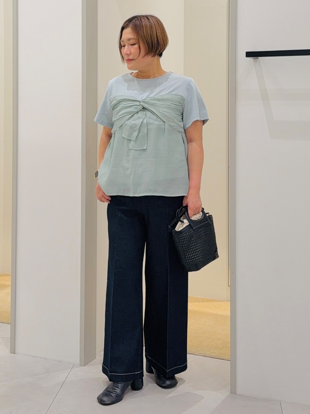 グリーン系のTシャツ/カットソー、ブラック系のデニムパンツ、グリーン系のショルダーバッグを着用したレディースの夏コーディネートの2枚目の写真