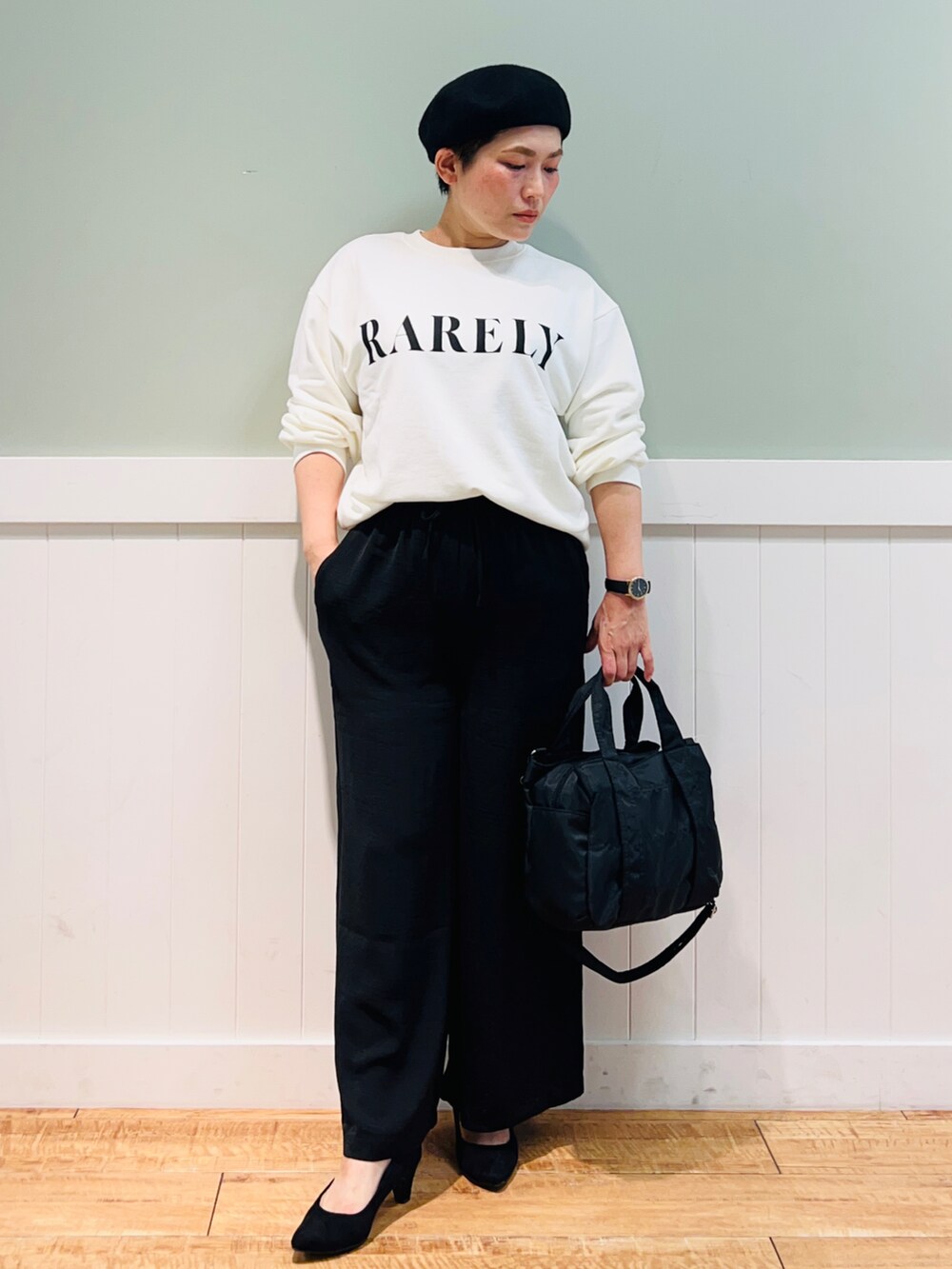 ホワイト系のスウェット、ブラック系のトートバッグ、ブラック系のパンツを着用したレディースの秋コーディネートの4枚目の写真