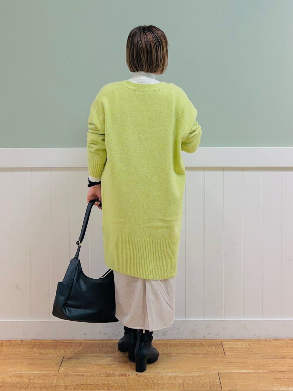 ブラック系のニット/セーター、イエロー系のカーディガン/ボレロ、ベージュ系のスカートを着用したレディースの秋コーディネートの4枚目の写真