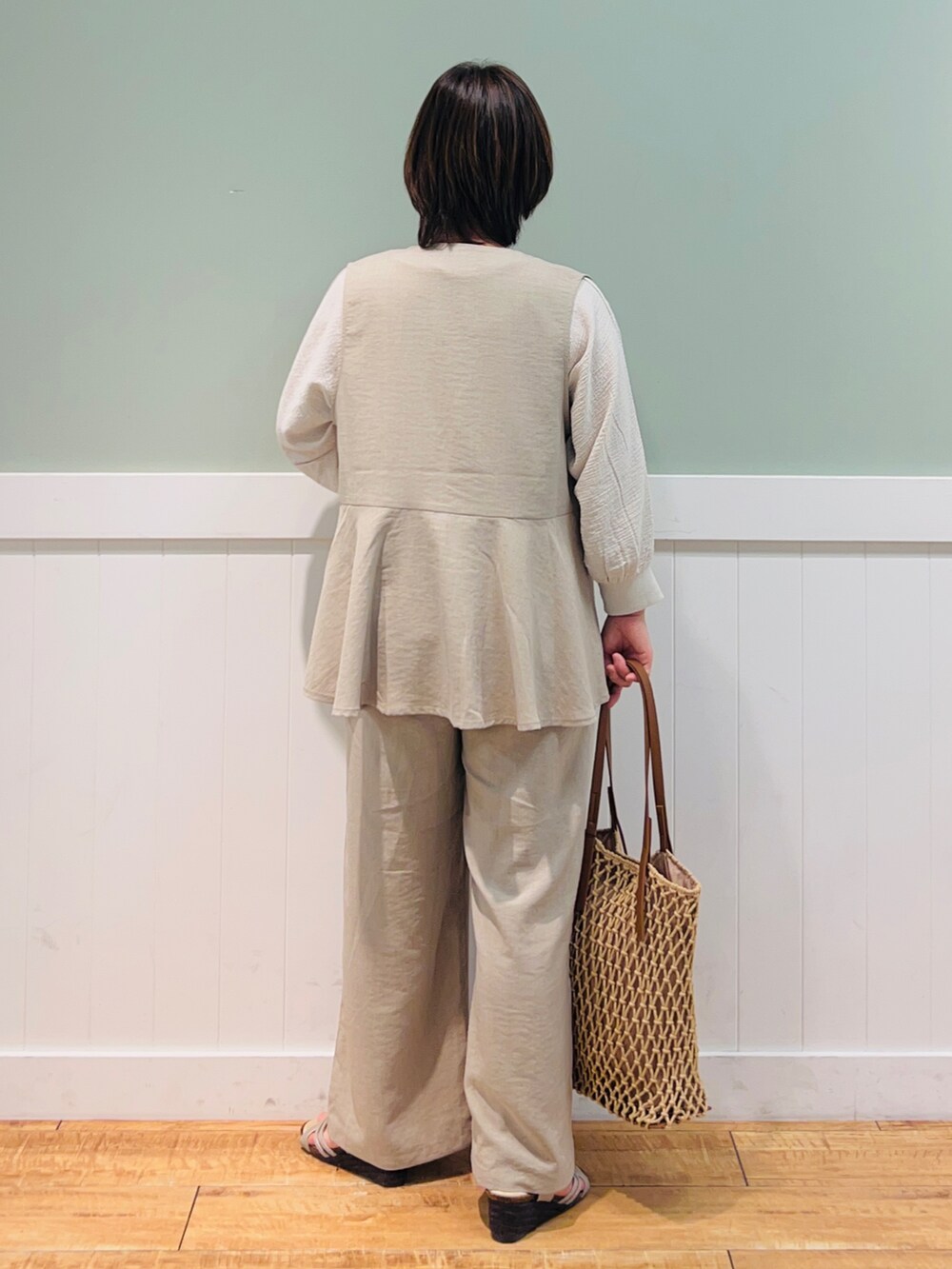 ベージュ系のベスト、ブラウン系のトートバッグ、ベージュ系のシャツ/ブラウスを着用したレディースの春コーディネートの2枚目の写真