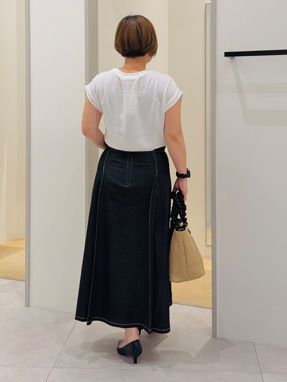 ホワイト系のTシャツ/カットソー、ブラック系のデニムスカート、ブラック系のパンプスを着用したレディースの夏コーディネートの4枚目の写真