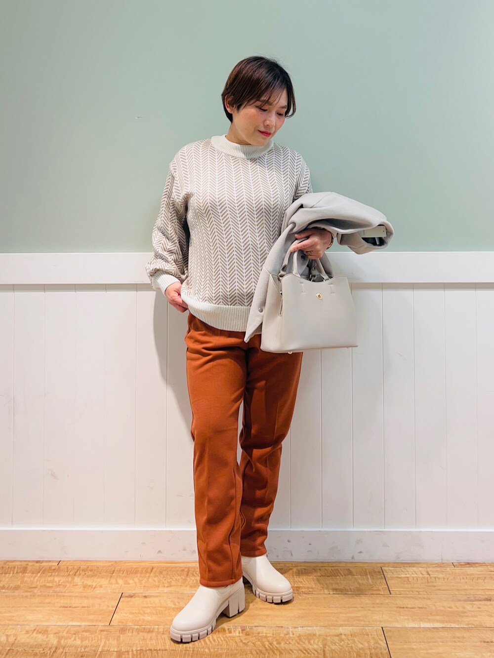 ベージュ系のノーカラーコート、ホワイト系のニット/セーター、グレー系のトートバッグを着用したレディースの冬コーディネートの3枚目の写真