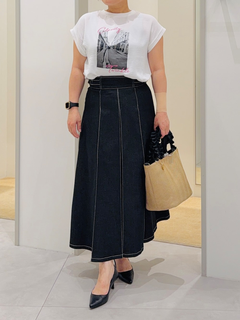 ホワイト系のTシャツ/カットソー、ブラック系のデニムスカート、ブラック系のパンプスを着用したレディースの夏コーディネートの5枚目の写真