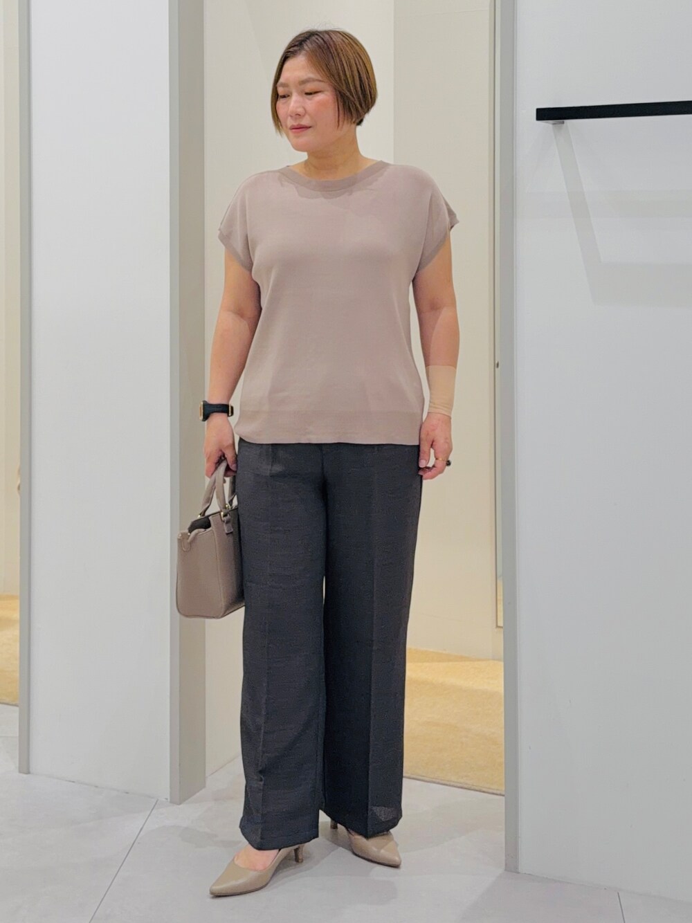 ベージュ系のニット/セーター、ブラック系のその他パンツ、ブラウン系のトートバッグを着用したレディースの夏コーディネートの2枚目の写真