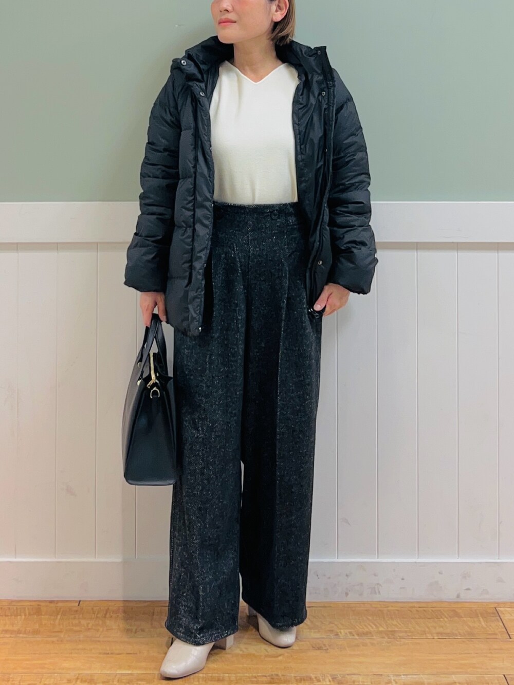 ブラック系のダウンジャケット/コート、ホワイト系のニット/セーター、ブラック系のトートバッグを着用したレディースの秋コーディネートの5枚目の写真