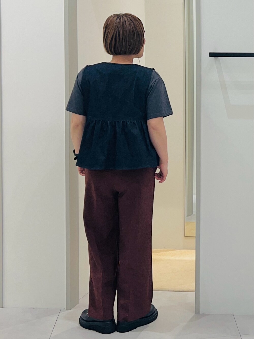 ブルー系のベスト、ブラック系のパンプス、ブラウン系のその他パンツを着用したレディースの春コーディネートの4枚目の写真