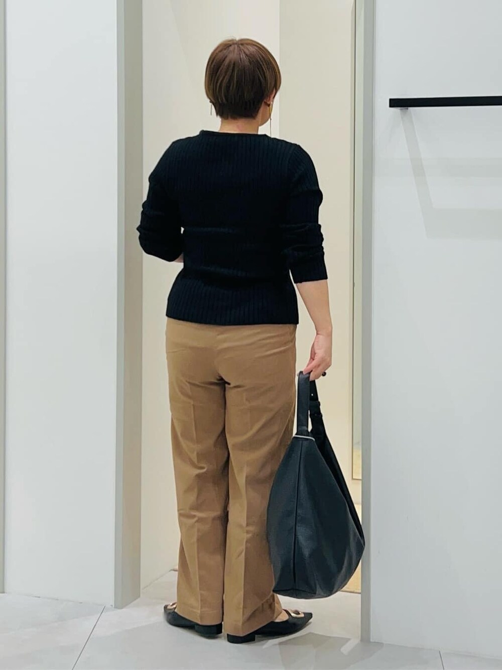 ブラック系のニット/セーター、ベージュ系のその他パンツ、ブラック系のトートバッグを着用したレディースの秋コーディネートの4枚目の写真