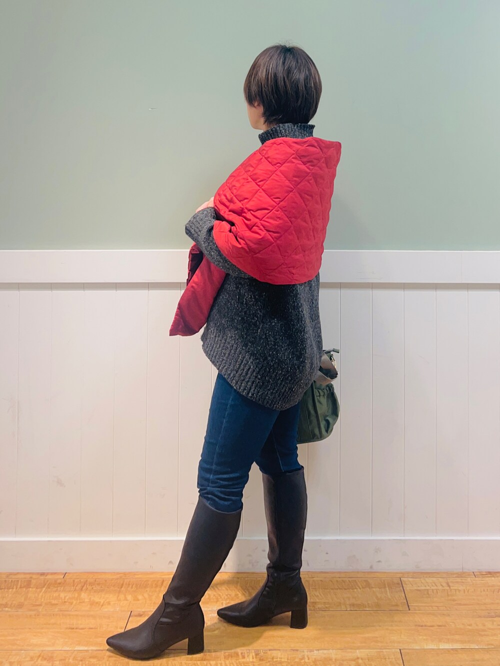 グレー系のニット/セーター、ブルー系のデニムパンツ、グリーン系のトートバッグを着用したレディースの冬コーディネートの2枚目の写真