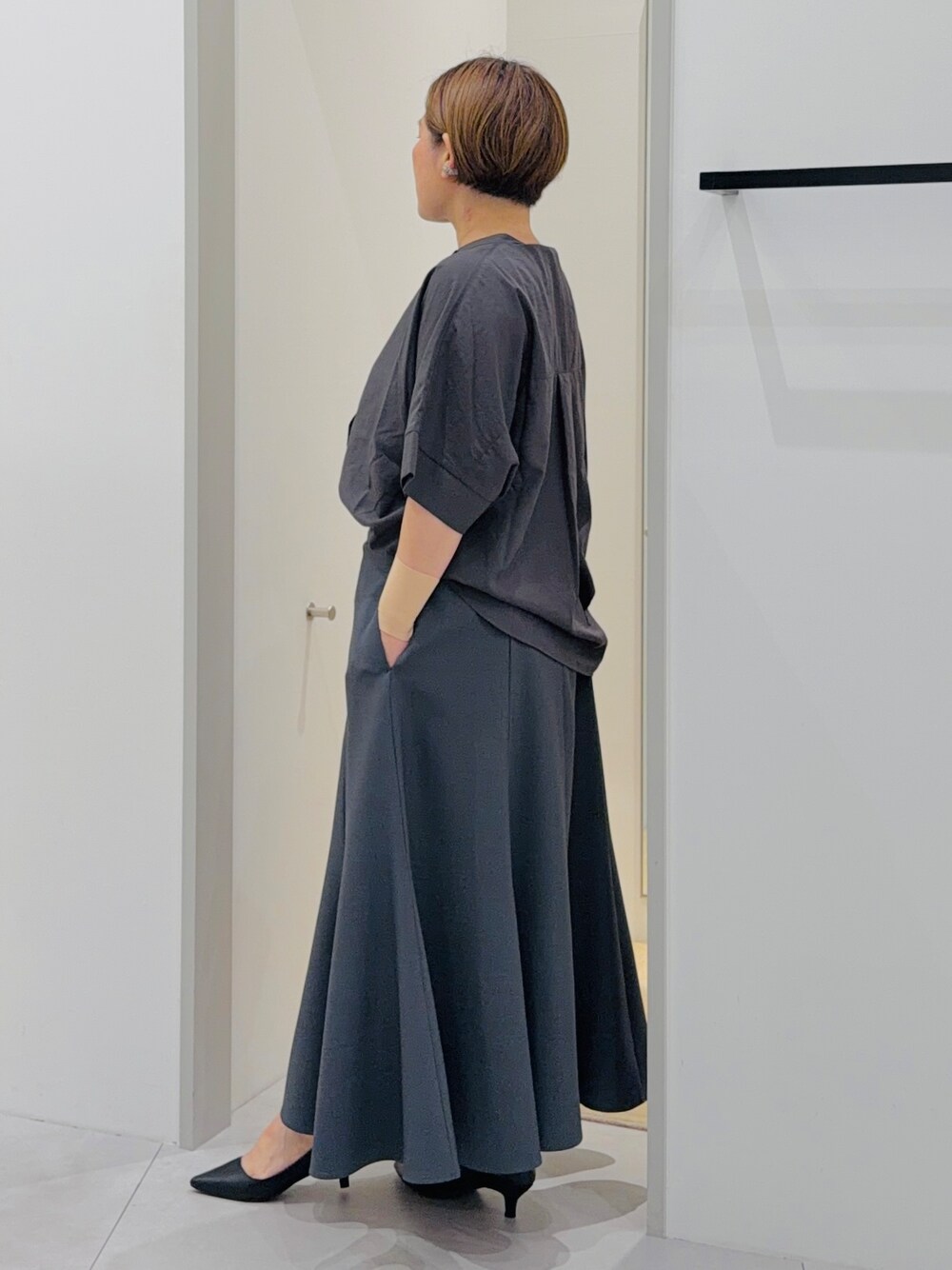 ブラック系のシャツ/ブラウス、グレー系のスカート、グレー系のショルダーバッグを着用したレディースの夏コーディネートの4枚目の写真