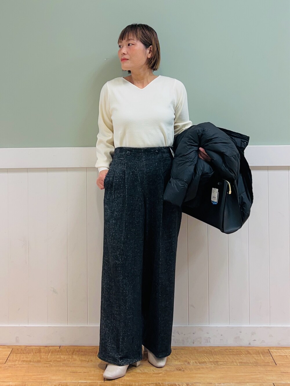 ブラック系のダウンジャケット/コート、ホワイト系のニット/セーター、ブラック系のトートバッグを着用したレディースの秋コーディネートの2枚目の写真