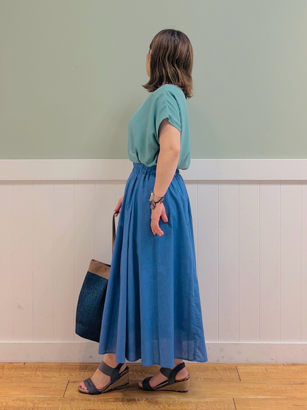 グリーン系のTシャツ/カットソー、ブラウン系のトートバッグ、ブルー系のスカートを着用したレディースの夏コーディネートの2枚目の写真