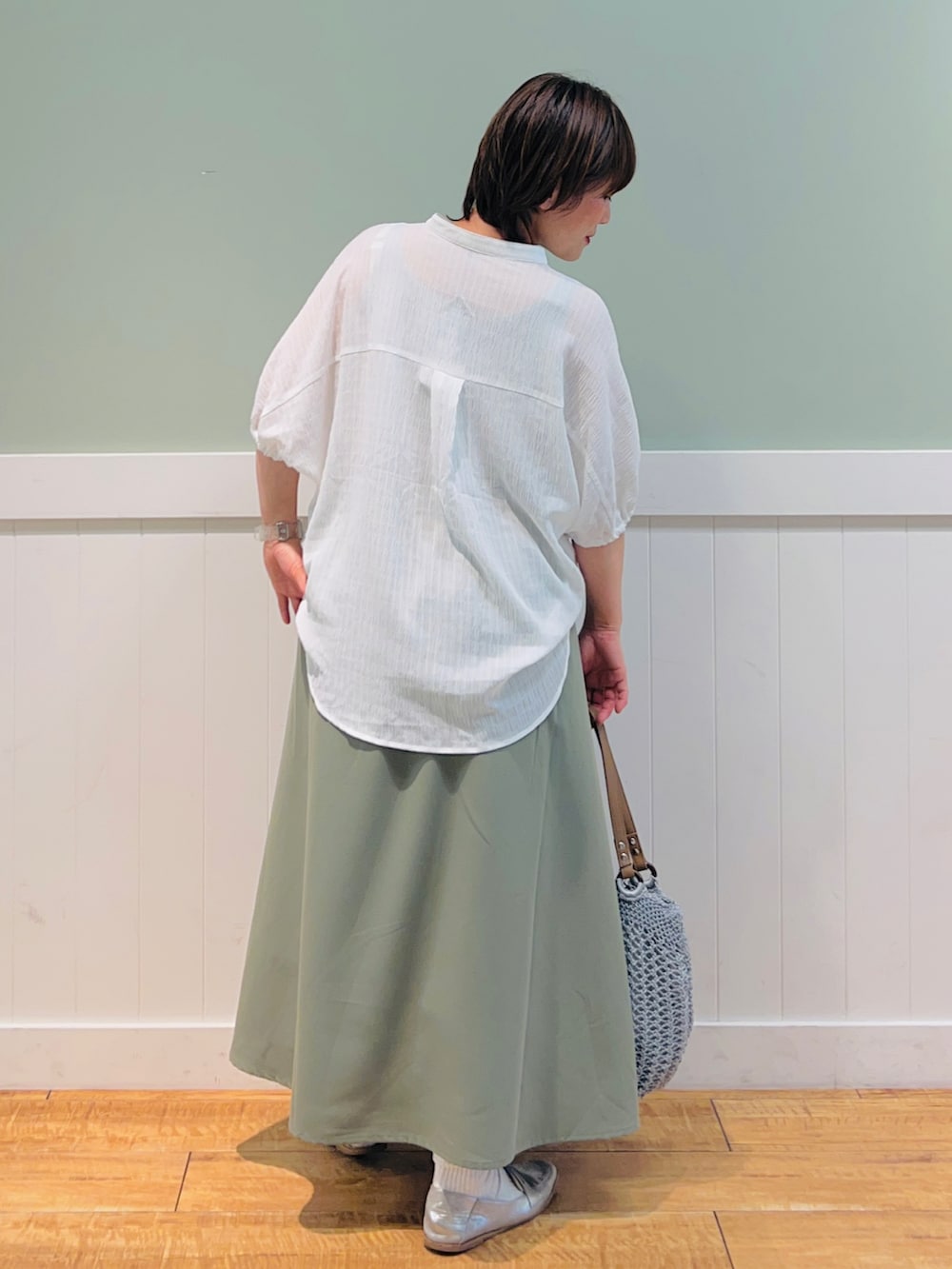 ホワイト系のシャツ/ブラウス、グリーン系のスカート、グレー系のトートバッグを着用したレディースの春コーディネートの2枚目の写真