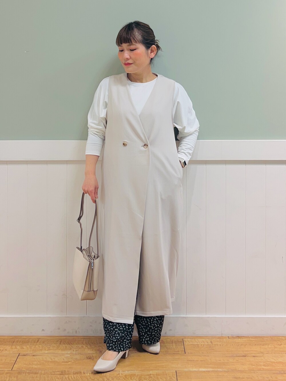 ベージュ系のベスト、ホワイト系のTシャツ/カットソー、ベージュ系のショルダーバッグを着用したレディースの春コーディネートの2枚目の写真