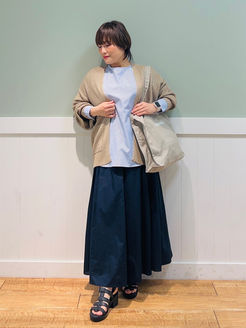 ブルー系のシャツ/ブラウス、ベージュ系のカーディガン/ボレロ、グレー系のトートバッグを着用したレディースの春コーディネートの4枚目の写真