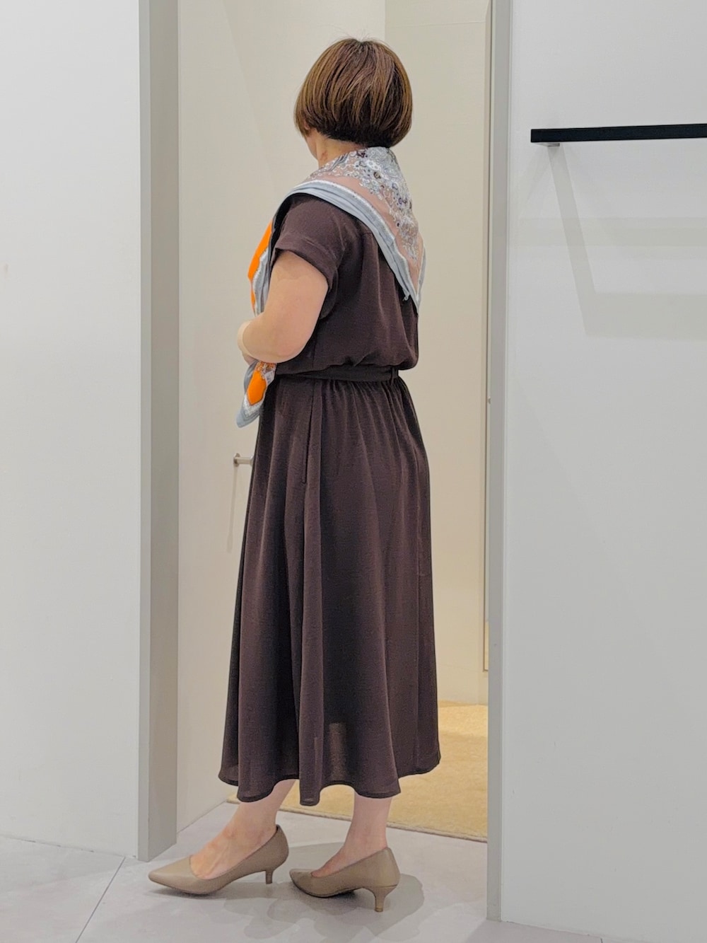 ブラウン系のワンピース、ブラウン系のハンドバッグ、ベージュ系のパンプスを着用したレディースの夏コーディネートの3枚目の写真