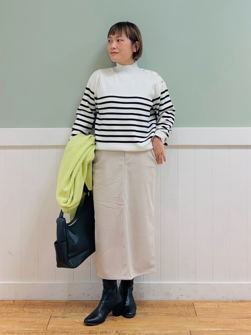 ブラック系のニット/セーター、イエロー系のカーディガン/ボレロ、ベージュ系のスカートを着用したレディースの秋コーディネートの3枚目の写真