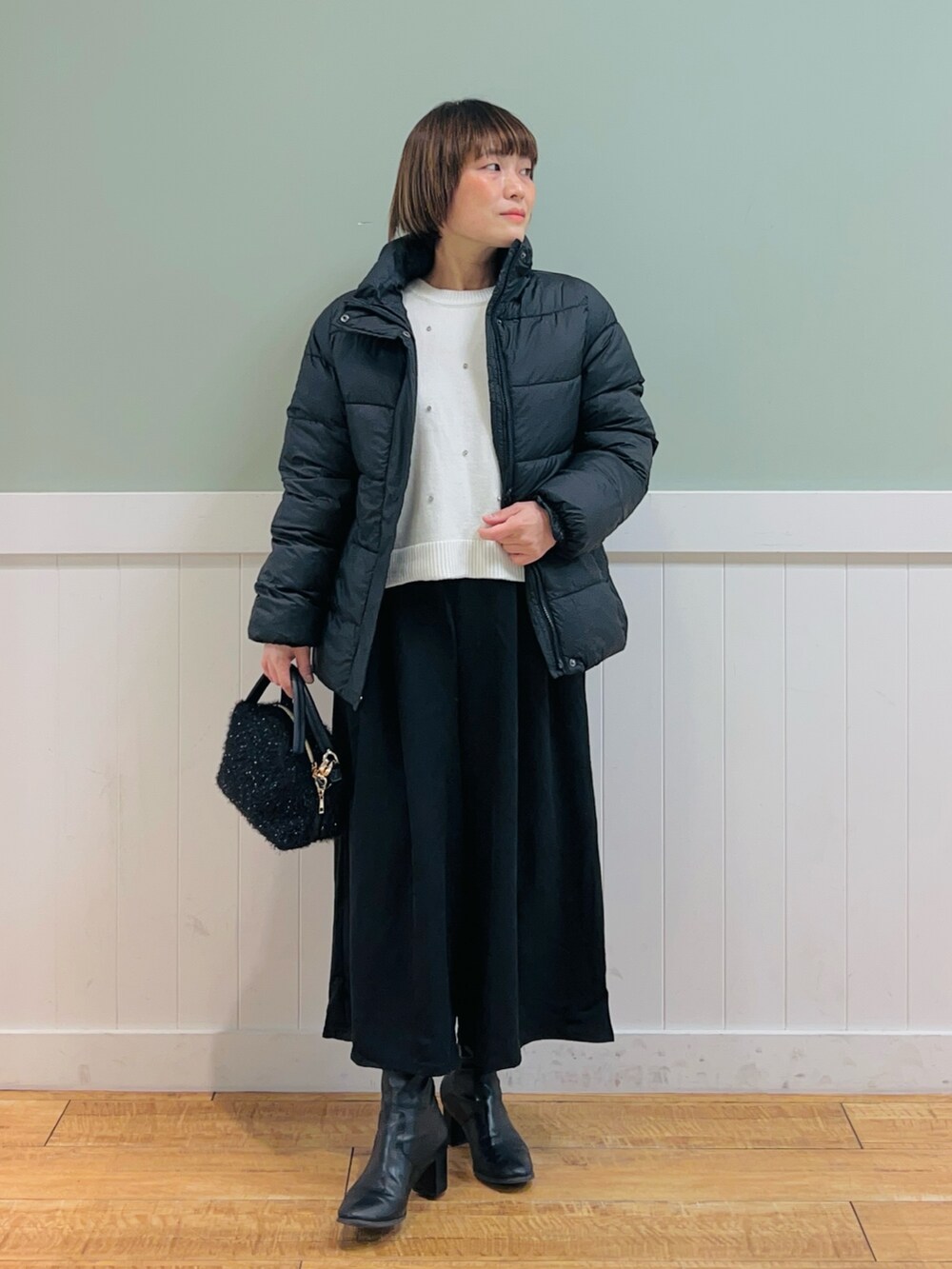 ブラック系のその他アウター、ホワイト系のニット/セーター、ブラック系のその他パンツを着用したレディースの冬コーディネートの2枚目の写真