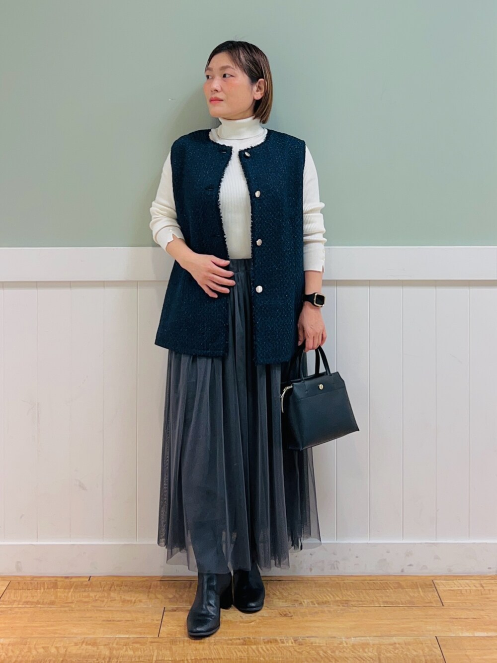 ホワイト系のニット/セーター、ブルー系のベスト、ブラック系のトートバッグを着用したレディースの冬コーディネートの3枚目の写真