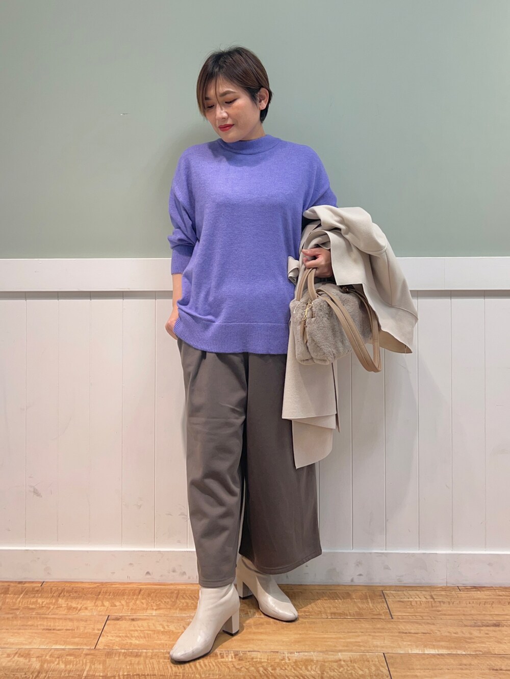 パープル系のニット/セーター、ベージュ系のチェスターコート、ベージュ系のショルダーバッグを着用したレディースの冬コーディネートの4枚目の写真