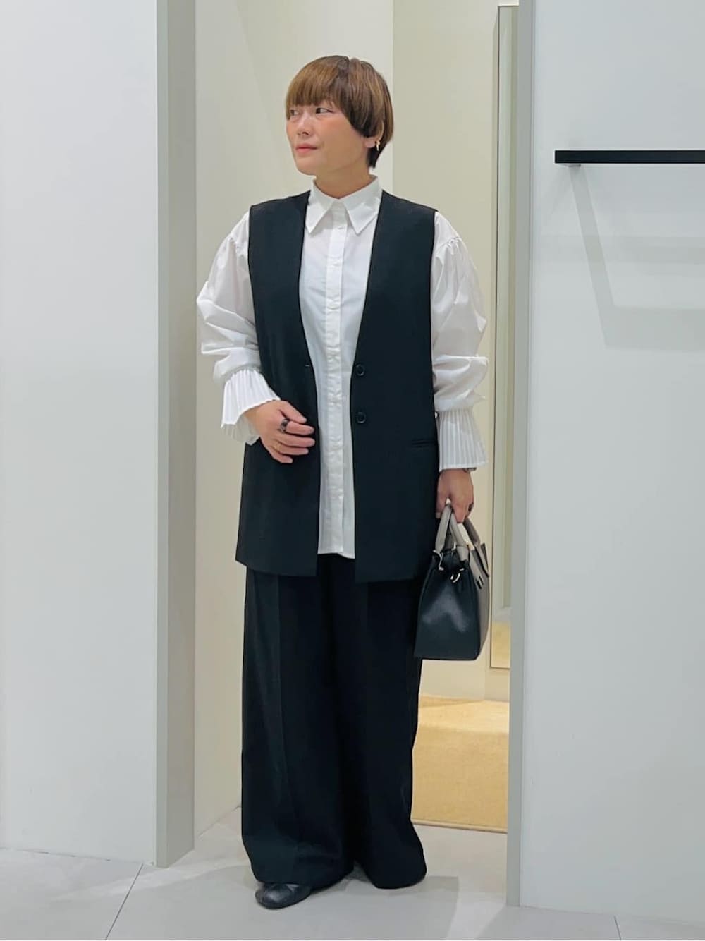 ブラック系のベスト、ホワイト系のシャツ/ブラウス、ブラック系のその他パンツを着用したレディースの秋コーディネートの2枚目の写真