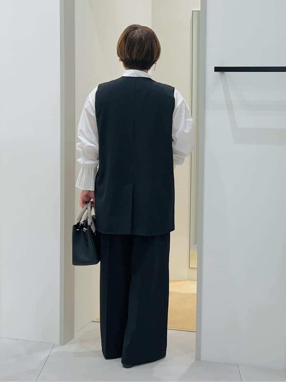 ブラック系のベスト、ホワイト系のシャツ/ブラウス、ブラック系のその他パンツを着用したレディースの秋コーディネートの4枚目の写真