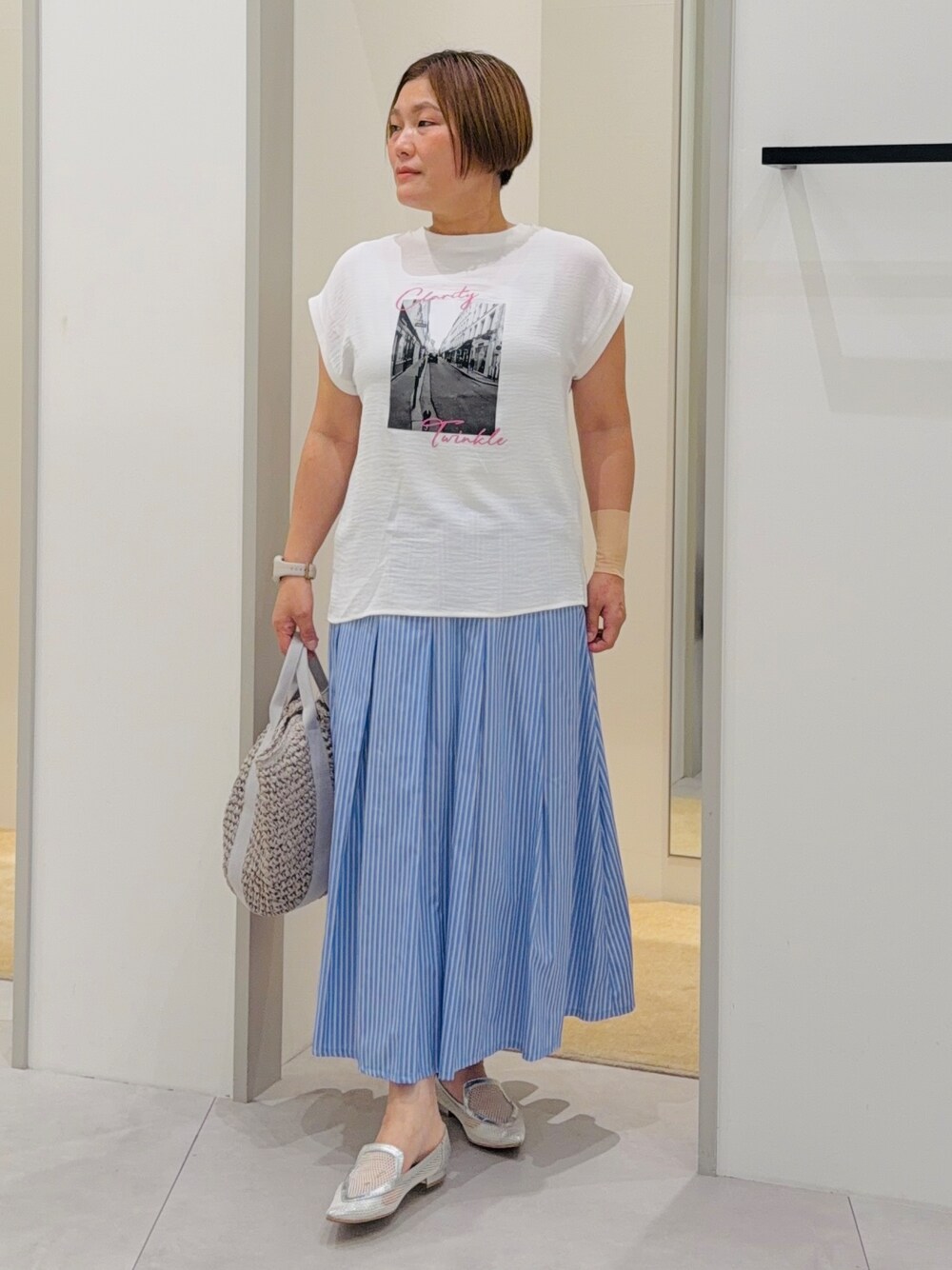 ホワイト系のTシャツ/カットソー、ブルー系のスカート、グレー系のトートバッグを着用したレディースの夏コーディネートの3枚目の写真