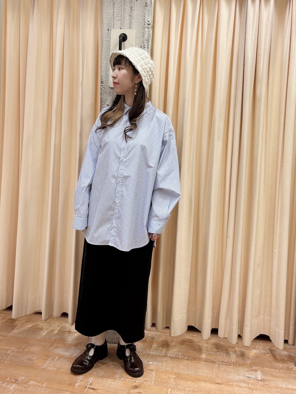 ブルー系のシャツ/ブラウス、ブラック系のスカート、ホワイト系のハットを着用したレディースの春コーディネートの2枚目の写真