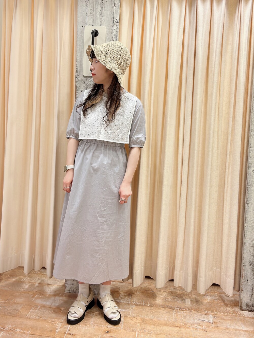 グレー系のワンピース、ホワイト系のサンダル、ホワイト系の帽子を着用したレディースの春コーディネートの3枚目の写真