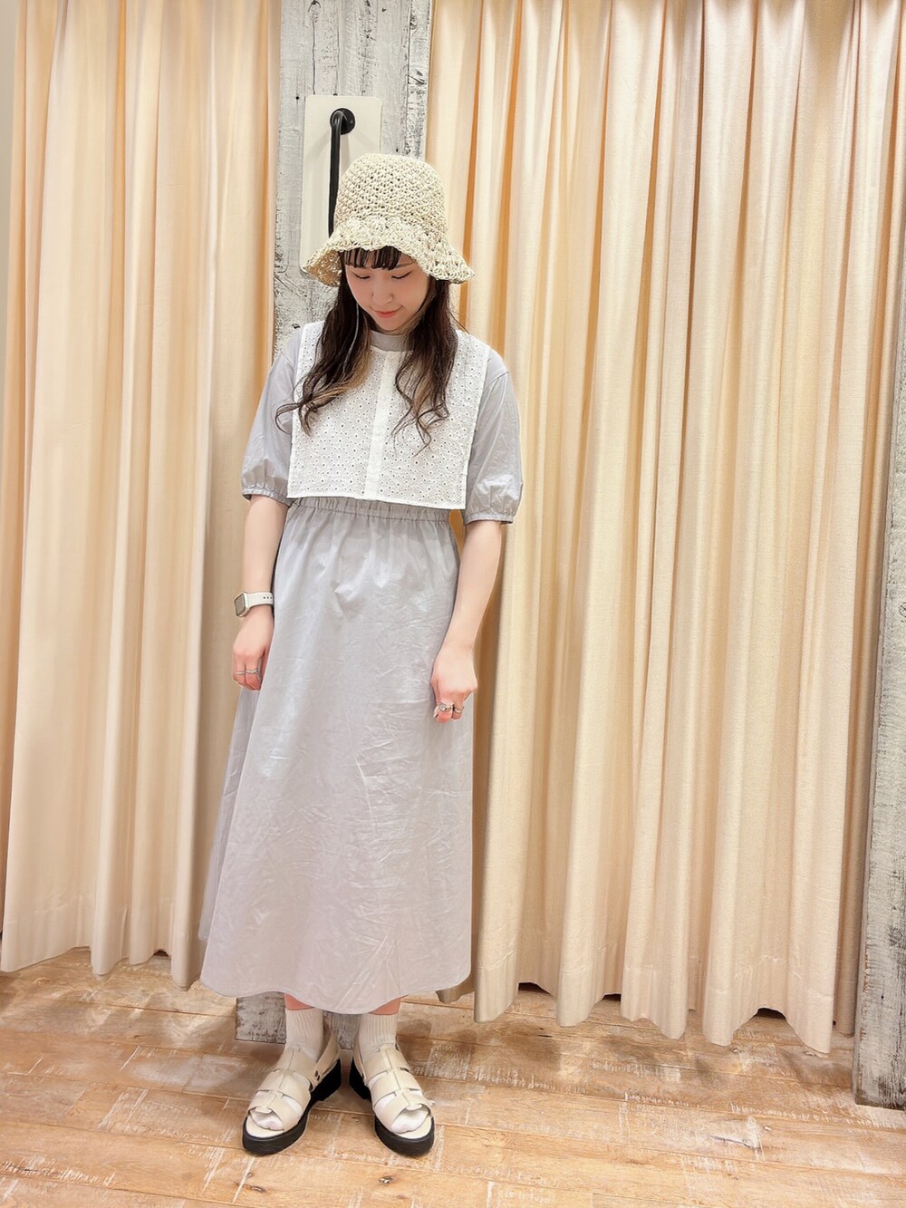 グレー系のワンピース、ホワイト系のサンダル、ホワイト系の帽子を着用したレディースの春コーディネートの2枚目の写真