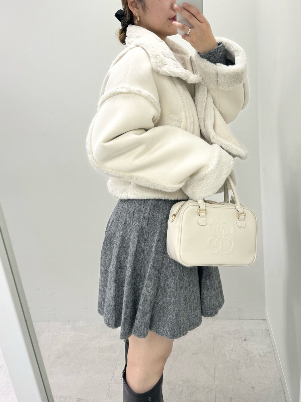 ホワイト系のムートンコート、グレー系のワンピース、ブラック系のブーツを着用したレディースの冬コーディネートの2枚目の写真