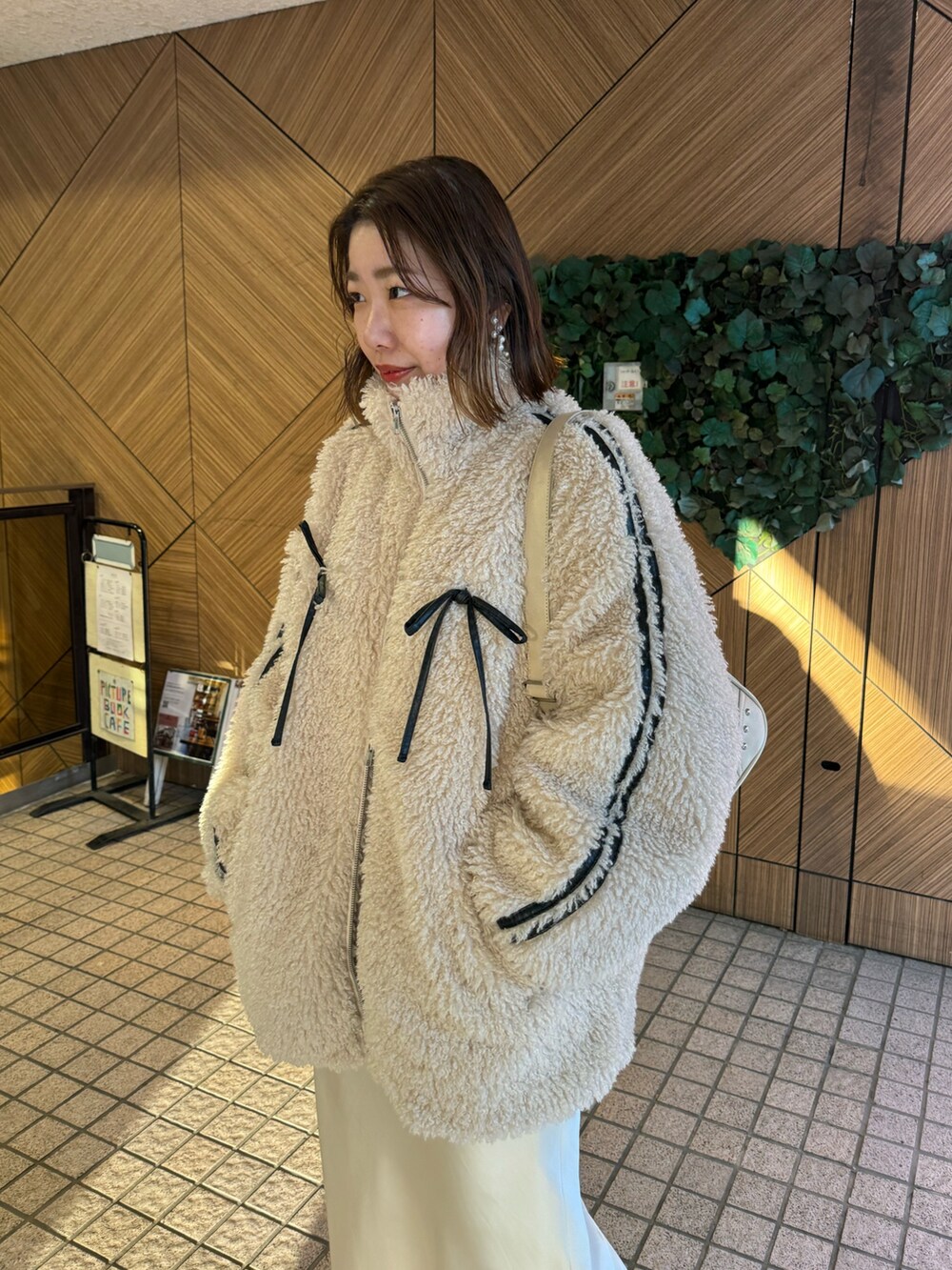 ホワイト系のショルダーバッグ、ホワイト系のスカート、ベージュ系のブルゾンを着用したレディースの冬コーディネートの2枚目の写真