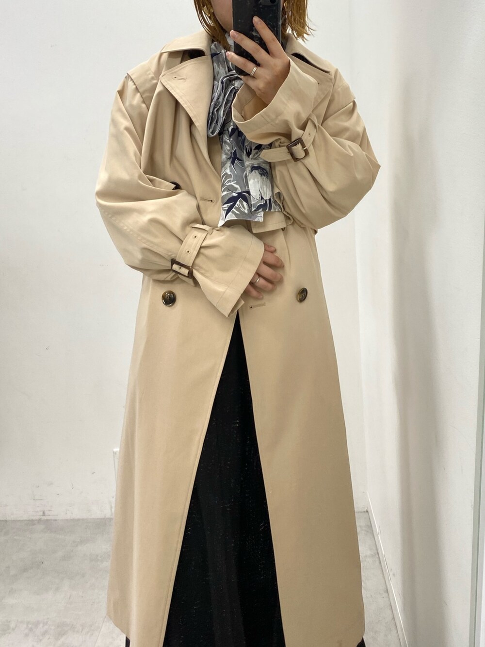 ベージュ系のトレンチコート、ブラック系のスカート、グレー系のシャツ/ブラウスを着用したレディースの春コーディネートの2枚目の写真