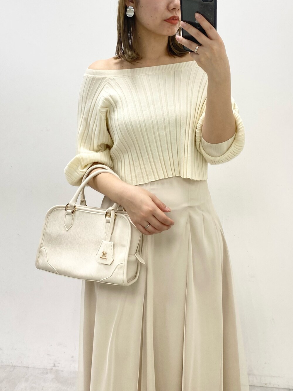 ホワイト系のワンピース、ベージュ系のスカート、ホワイト系のハンドバッグを着用したレディースの冬コーディネートの2枚目の写真