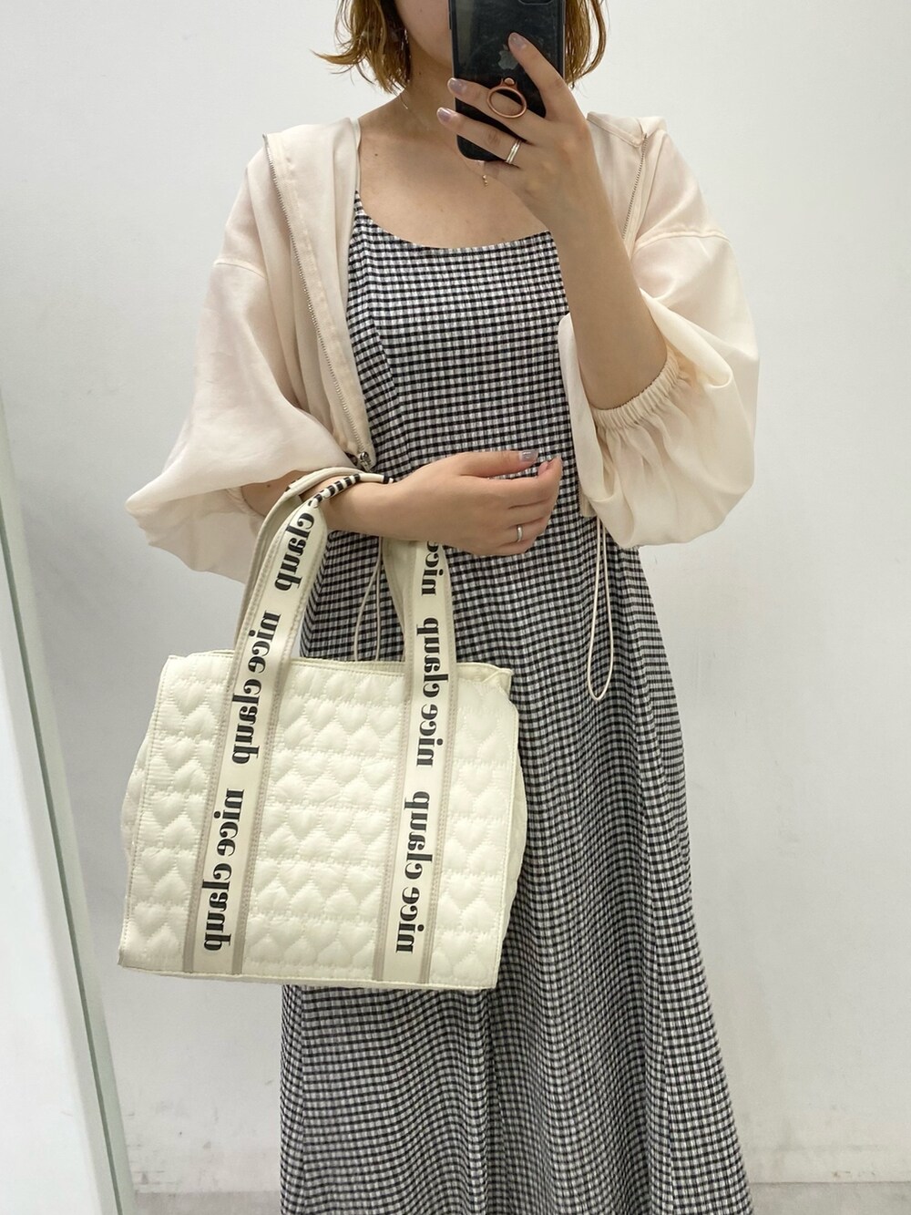 ブラック系のワンピース、ホワイト系のトートバッグ、ホワイト系のマウンテンパーカーを着用したレディースの夏コーディネートの2枚目の写真