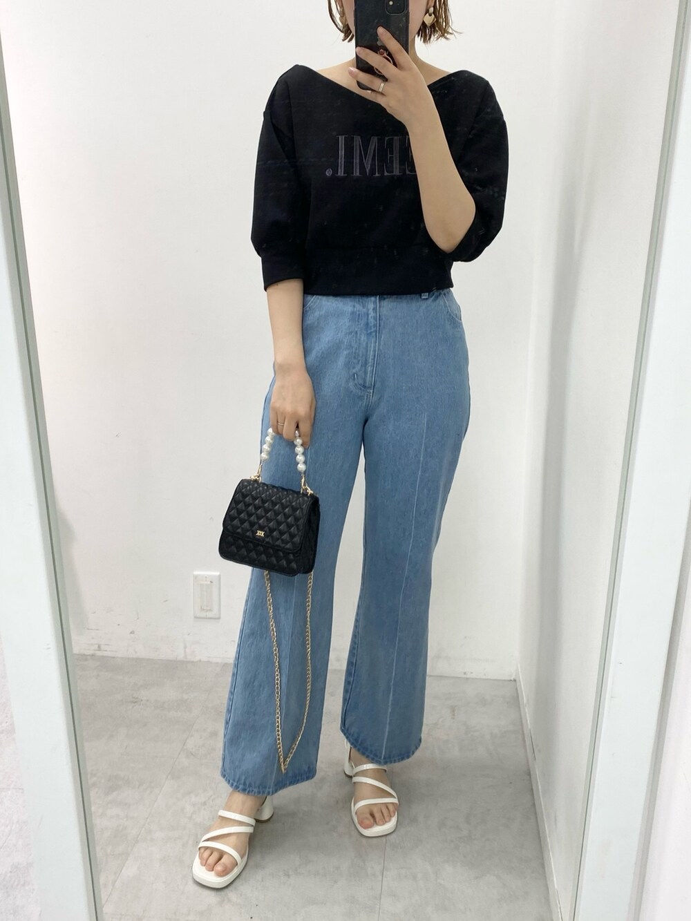 ブラック系のスウェット、ブルー系のデニムパンツを着用したレディースの春コーディネートの2枚目の写真