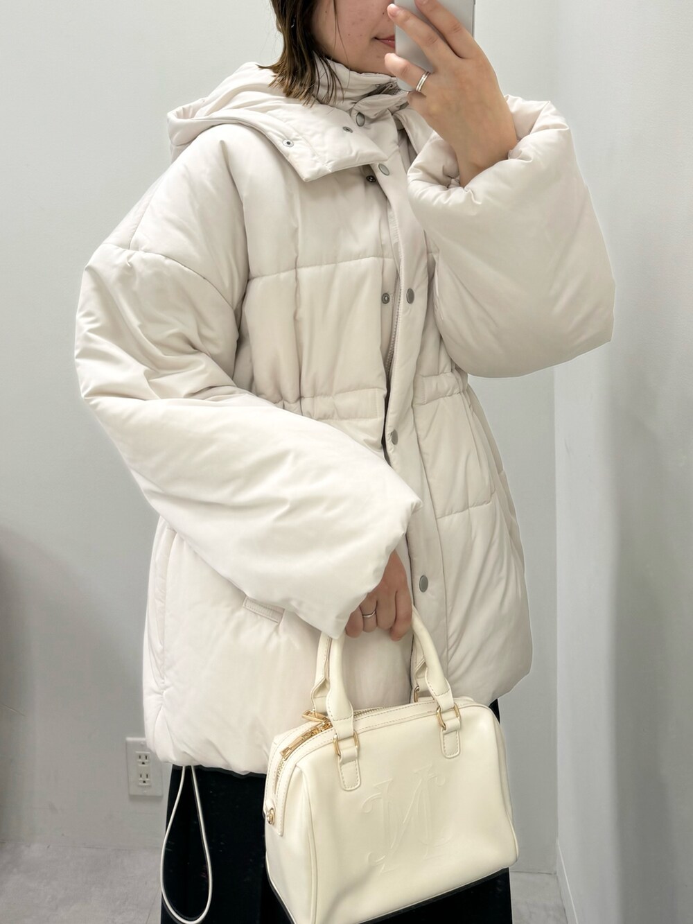 ベージュ系のダウンジャケット/コート、ブラック系のスカート、ブラック系のブーツを着用したレディースの冬コーディネートの2枚目の写真