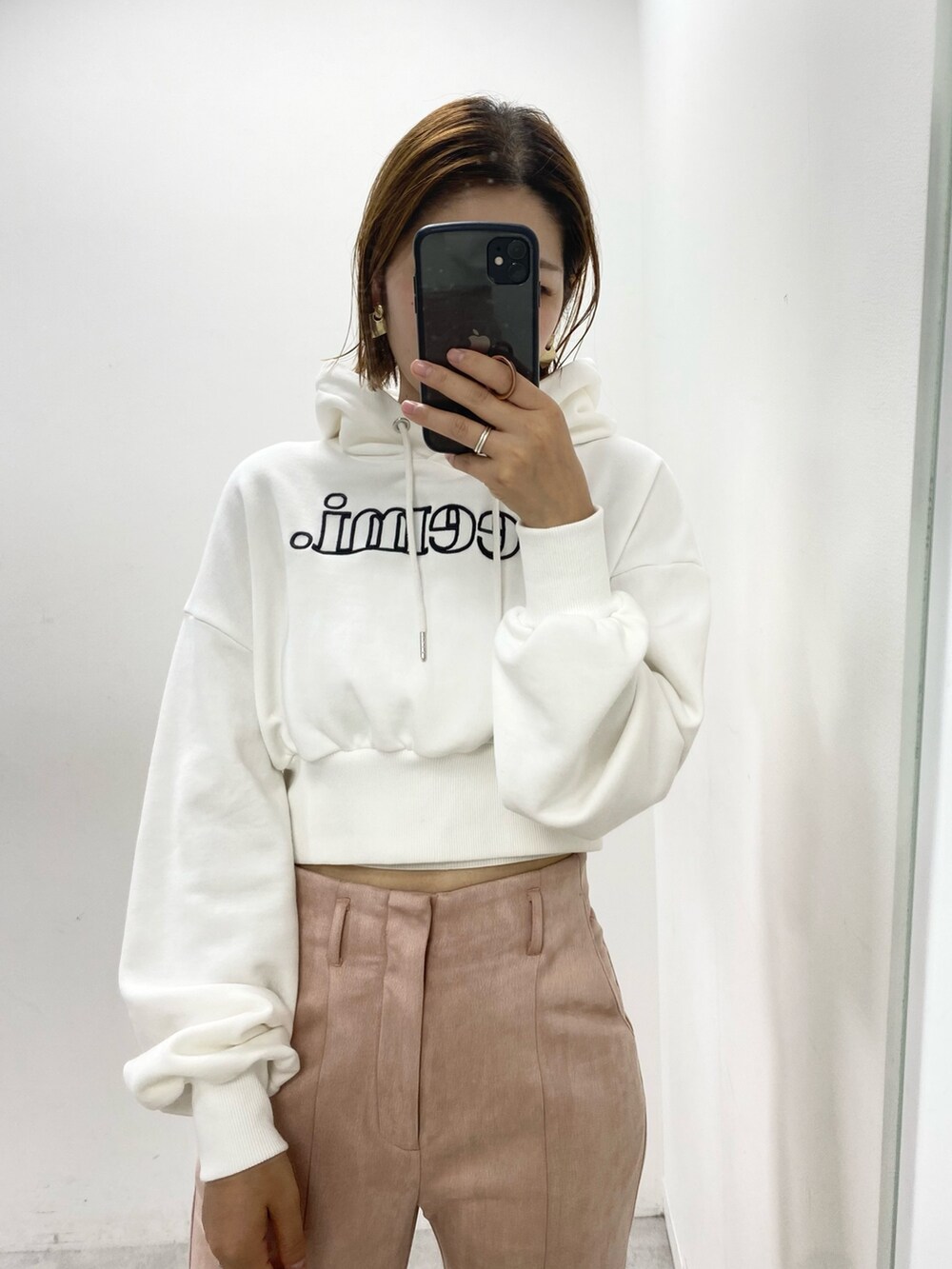 ホワイト系のパーカー、ピンク系のスラックス、ベージュ系のトートバッグを着用したレディースの秋コーディネートの2枚目の写真