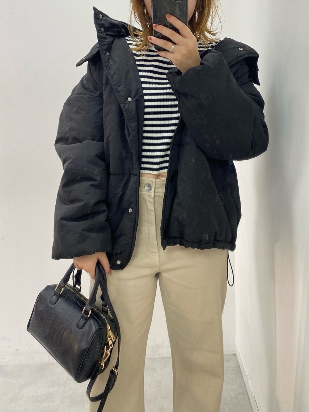 ブラック系のダウンジャケット/コート、ホワイト系のニット/セーター、ベージュ系のデニムパンツを着用したレディースの秋コーディネートの2枚目の写真