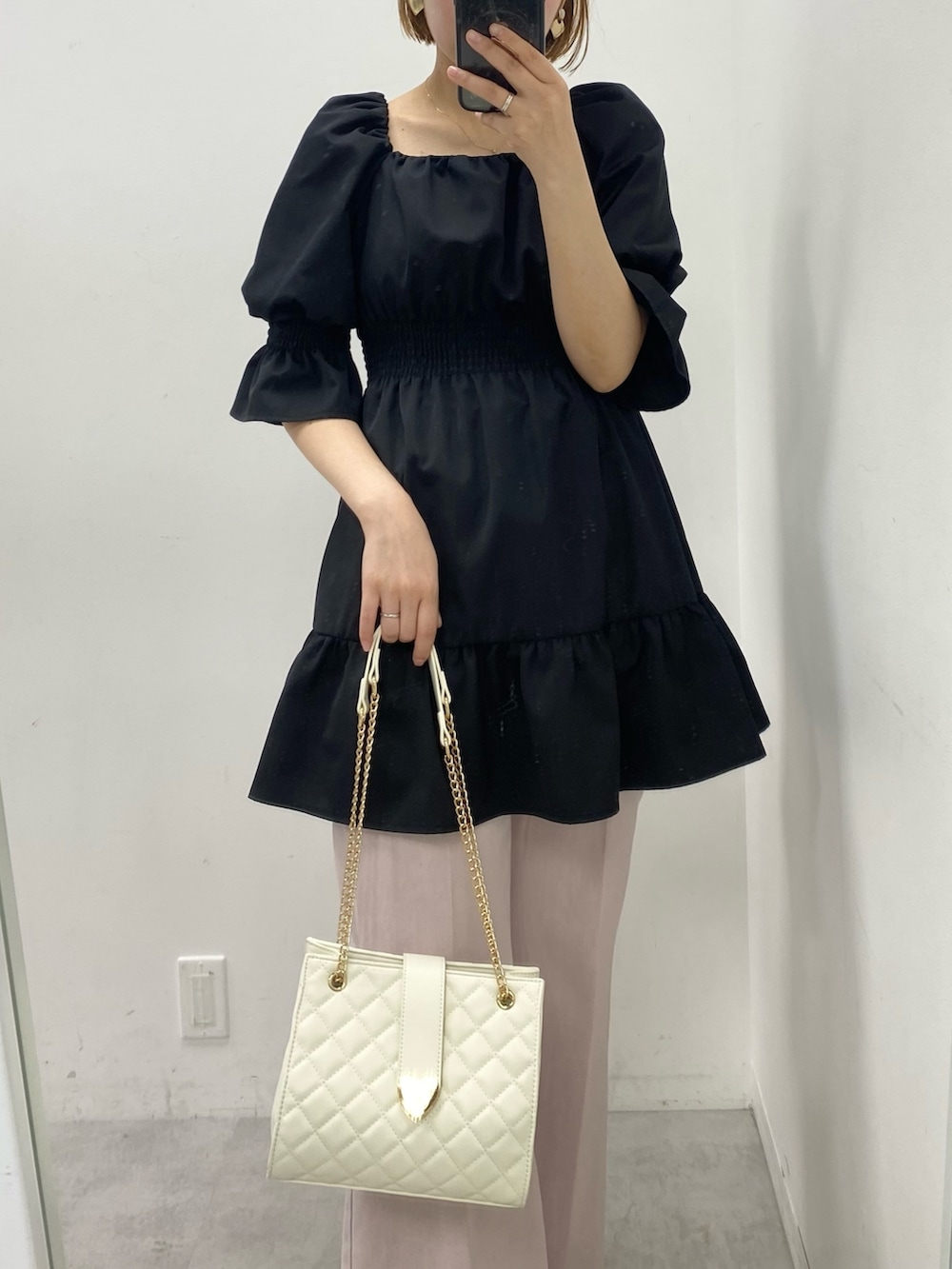 ブラック系のチュニック、ピンク系のデニムパンツ、ベージュ系のサンダルを着用したレディースの春コーディネートの2枚目の写真