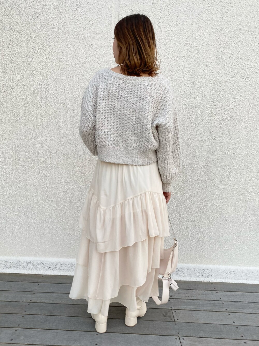 ホワイト系のショルダーバッグ、ホワイト系のスカート、ホワイト系のブーツを着用したレディースの冬コーディネートの2枚目の写真