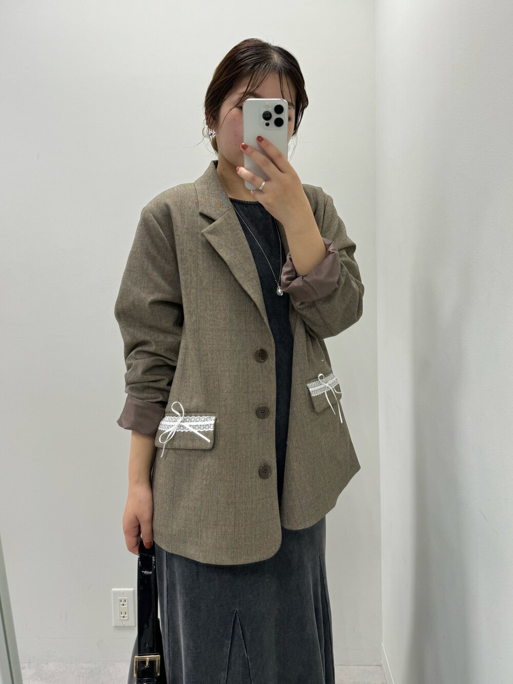 グレー系のワンピース、ブラウン系のテーラードジャケット、ブラック系のショルダーバッグを着用したレディースの夏コーディネートの2枚目の写真