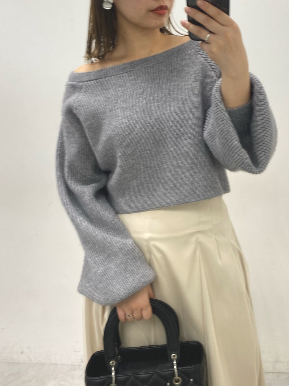 グレー系のワンピース、ベージュ系のスカート、ホワイト系のブーツを着用したレディースの冬コーディネートの2枚目の写真