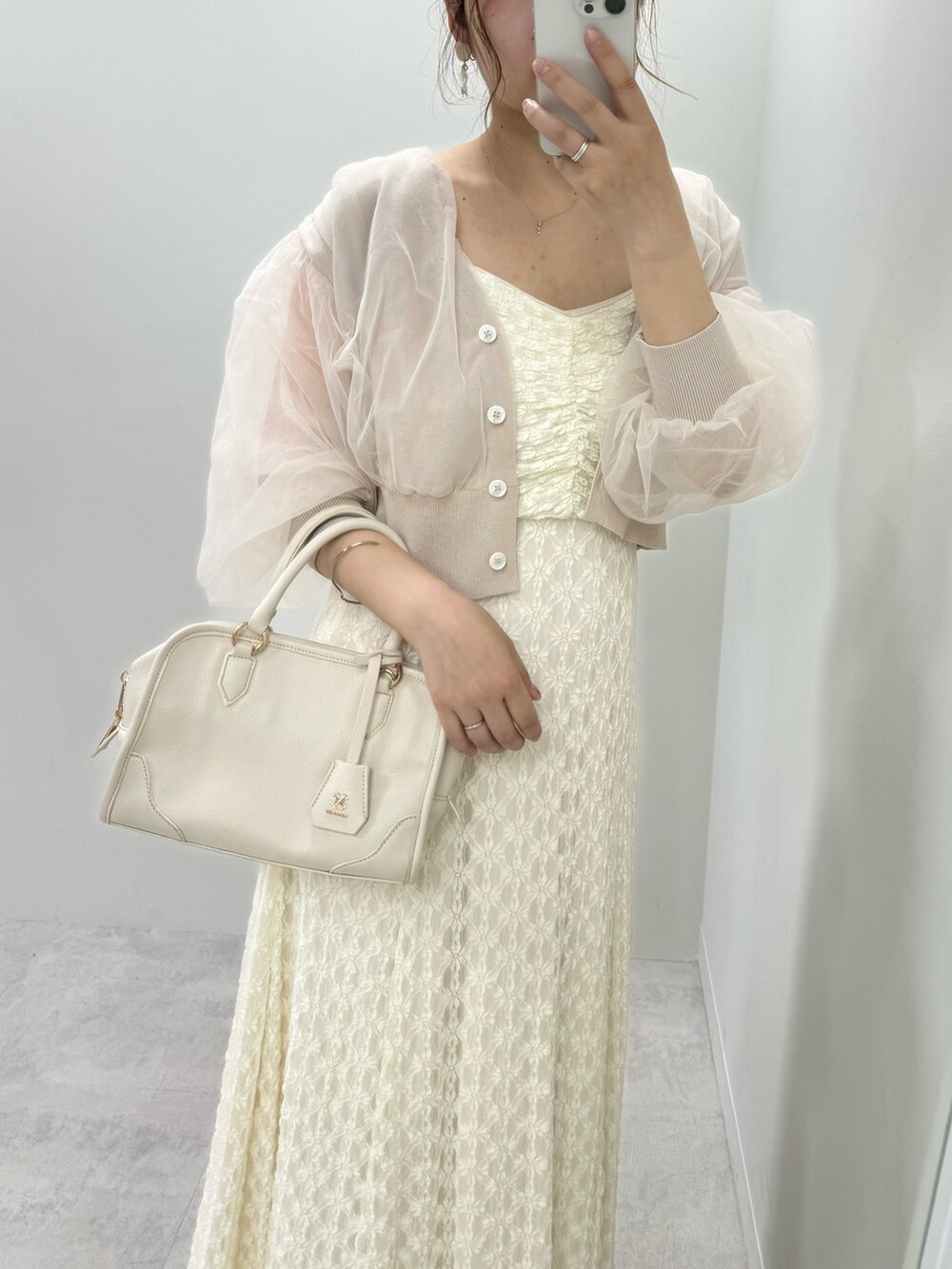 ホワイト系のワンピース、ベージュ系のカーディガン/ボレロ、ホワイト系のハンドバッグを着用したレディースの春コーディネートの2枚目の写真