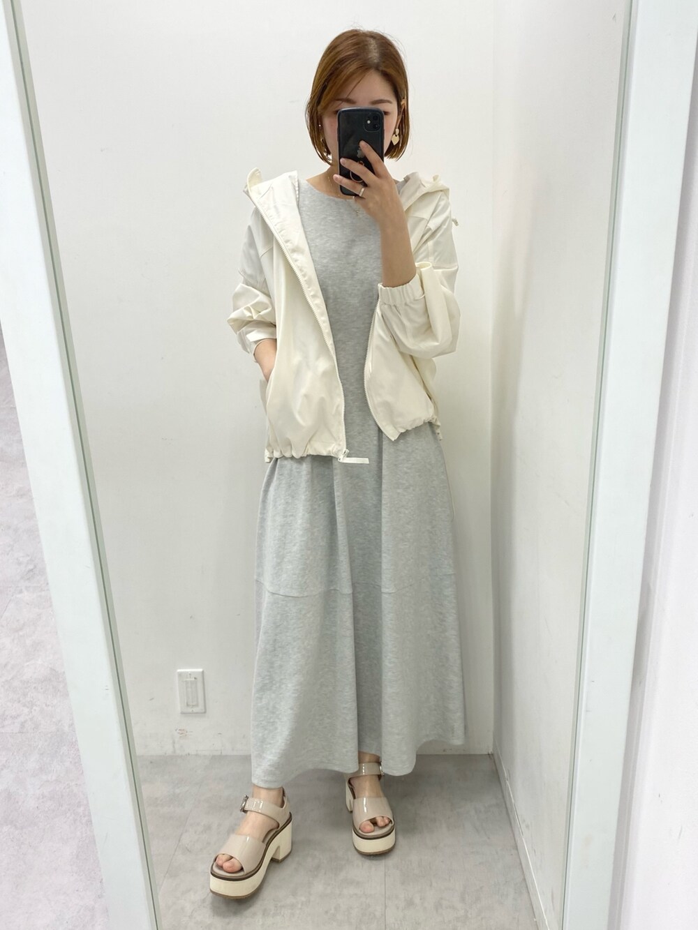 ホワイト系のマウンテンパーカー、グレー系のワンピースを着用したレディースの春コーディネートの2枚目の写真