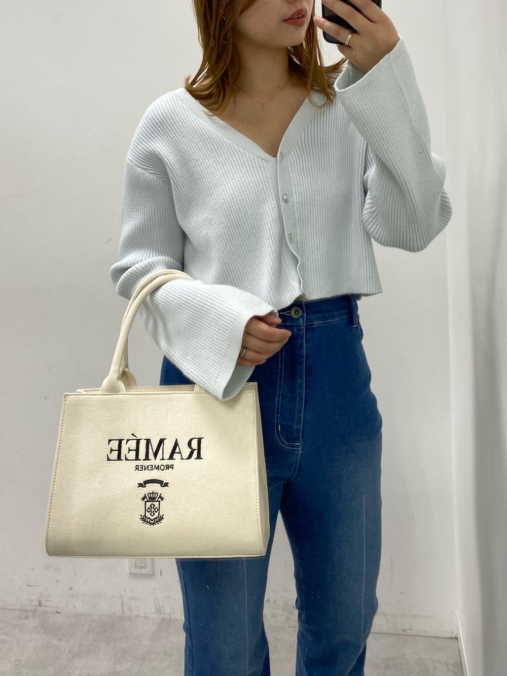 ブルー系のカーディガン/ボレロ、ブルー系のデニムパンツ、ホワイト系のトートバッグを着用したレディースの冬コーディネートの2枚目の写真