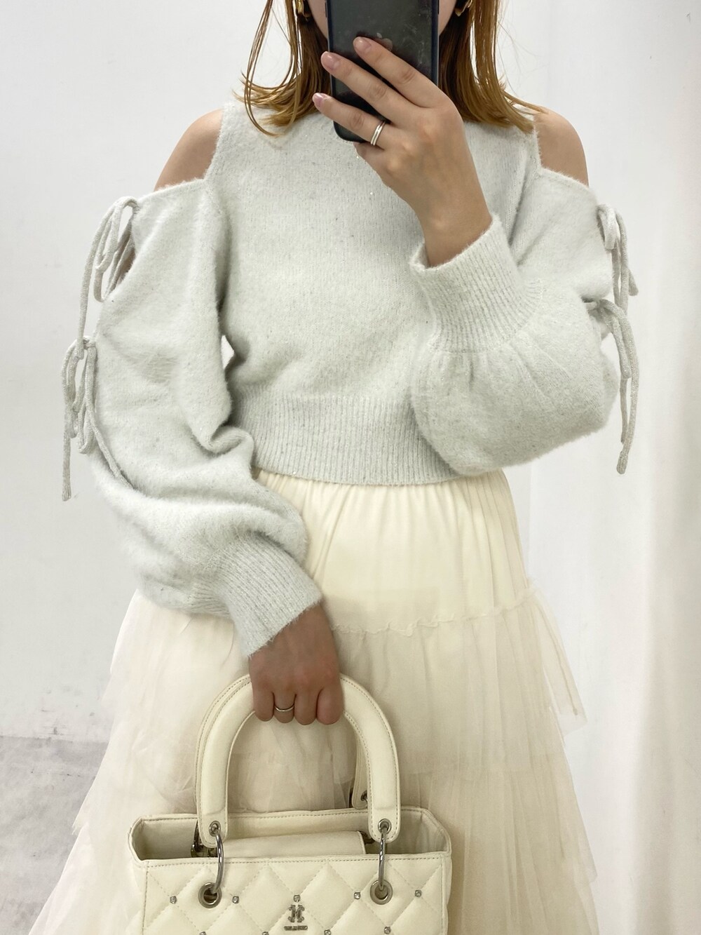 ホワイト系のスカート、グレー系のニット/セーター、ホワイト系のブーツを着用したレディースの冬コーディネートの2枚目の写真